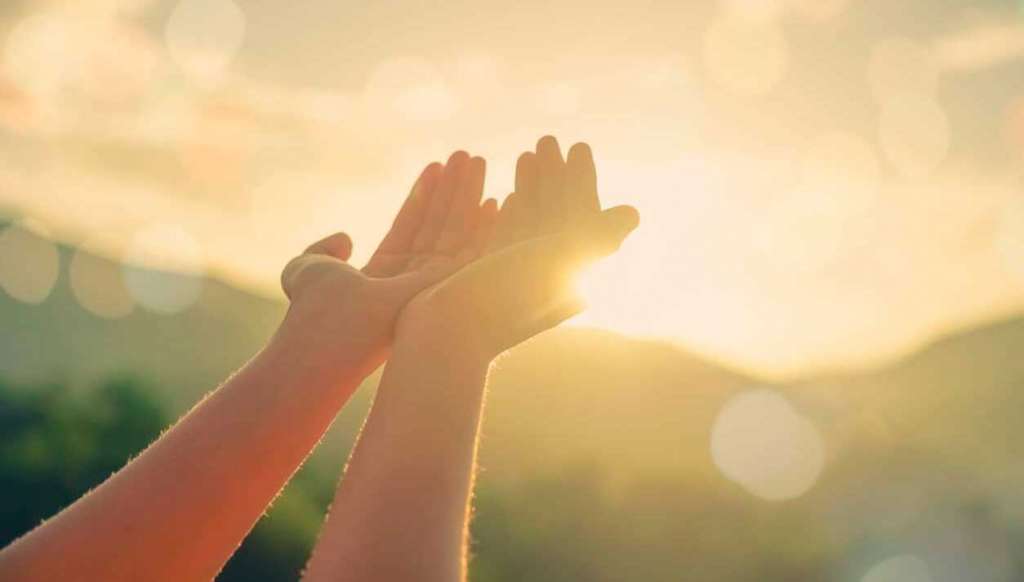 Dos manos en el sol bendiciendo para mejorar la Alimentación espiritual .