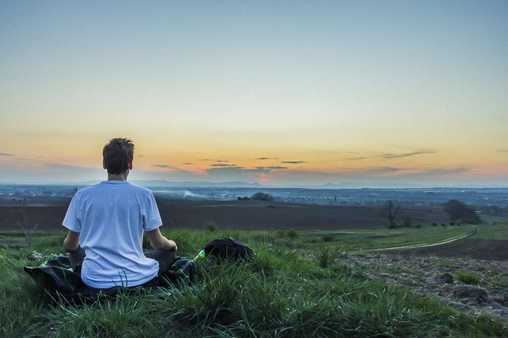 Hombre meditando observando un paisaje y realizando la meditación de consciencia abierta